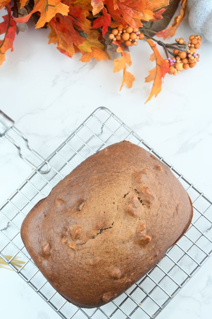 a loaf of bread sitting on top of a cooling rack next to an orange flower