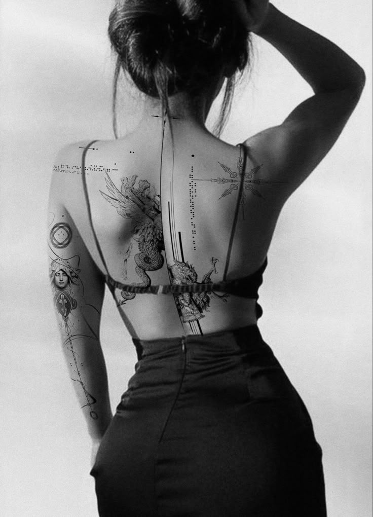 the back of a woman's body with tattoos on it