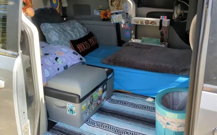 the inside of a van with luggage and blankets on it's bed area,