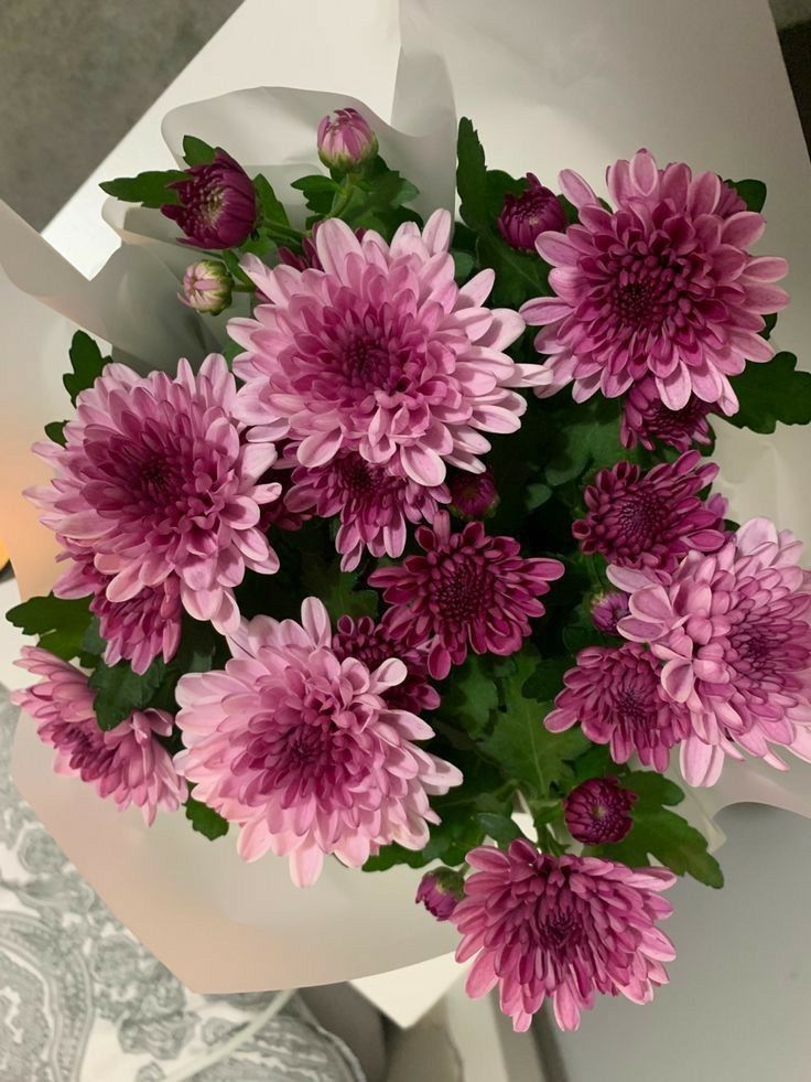 a bouquet of pink flowers sitting on top of a white table next to a candle