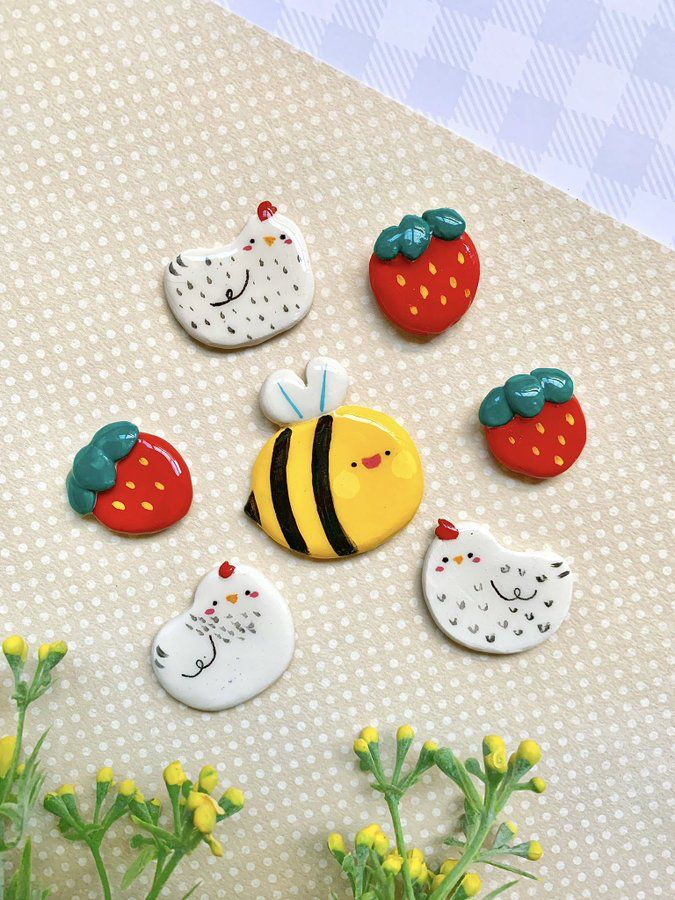 some little magnets that are sitting on a table next to flowers and plants with strawberries in them