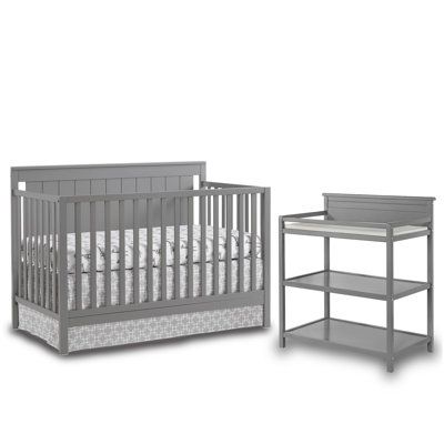 a baby crib with a changing table next to it and an end table on the side