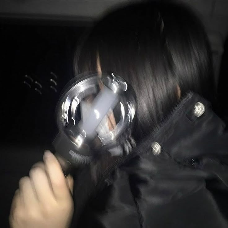 a woman is looking through a magnifying glass in the dark with her hand