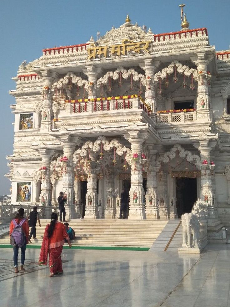 people walking in front of an ornate white building