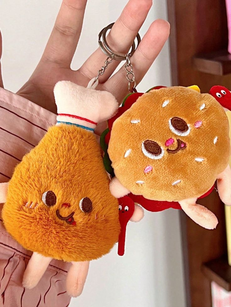 two stuffed animals are attached to a keychain in the shape of a hamburger and a burger