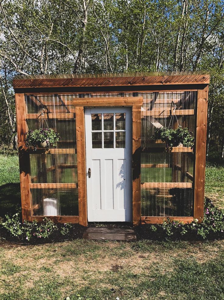 a small wooden structure sitting on top of a grass covered field next to a white door