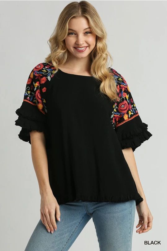 Step up your fashion game with our Floral Embroidered Round Neck Top! Crafted from a luxurious blend of 55% linen and 45% cotton, this top offers both comfort and style. The full front and back of this gorgeous top is a lovely solid go with anything black which provides a chic backdrop for the vibrant, multi-colored embroidery on the sleeves. The unfinished frayed hem adds a trendy, casual touch. Perfect for any occasion, this top is sure to become a staple in your wardrobe. Models are wearing s Embroidered Cotton Tops For Spring, Black Summer Blouse With Embroidered Sleeves, Black Cotton Tops With Embroidered Sleeves, Black Embroidered Hem Top For Summer, Casual Black Top With Embroidered Hem, Black Bohemian Top With Embroidered Hem, Bohemian Tops With Embroidered Hem And Relaxed Fit, Bohemian Tops With Embroidered Hem In Relaxed Fit, Bohemian Tops With Embroidered Sleeves For Vacation