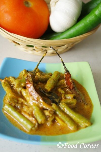 green beans and tomatoes are in a sauce on a blue plate next to other vegetables