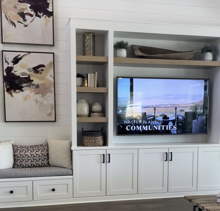 a living room with built in cabinets and a flat screen tv mounted on the wall