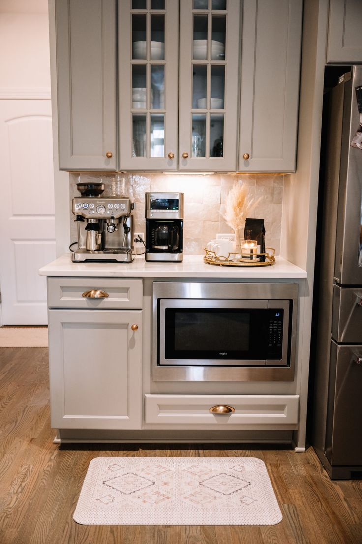 a kitchen with gray cabinets and white counter tops is pictured in this image, there is a rug on the floor next to the oven