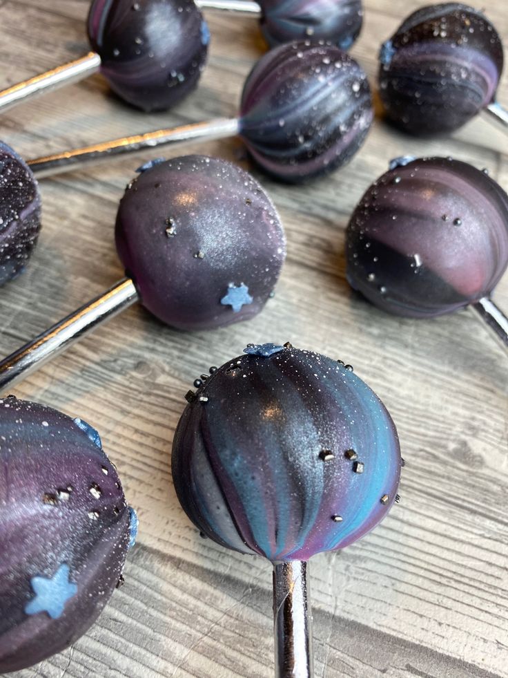 some purple cake pops sitting on top of a wooden table