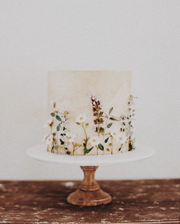 a white cake with flowers on it sitting on top of a wooden table