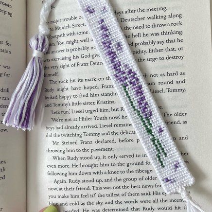 an open book with a tasseled beaded bookmark on top of it