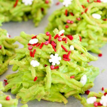 some green cookies with red and white sprinkles on them sitting on a table