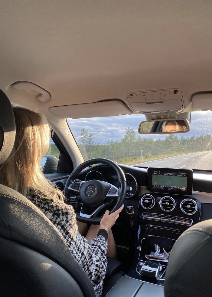 a woman is driving her car on the road