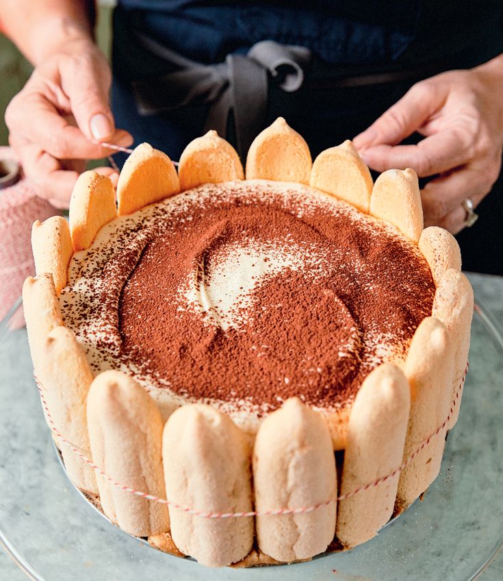 a person is decorating a cake with powdered sugar and cinnamon on the top