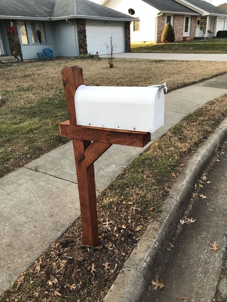 a mailbox sitting on the side of a road in front of a residential house