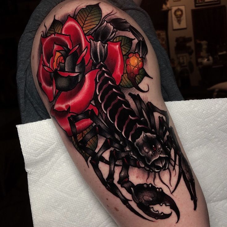 a man with a black and red tattoo on his arm that has roses in it