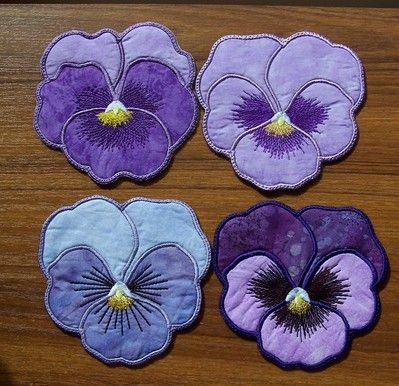 four purple and blue pansies on a wooden table