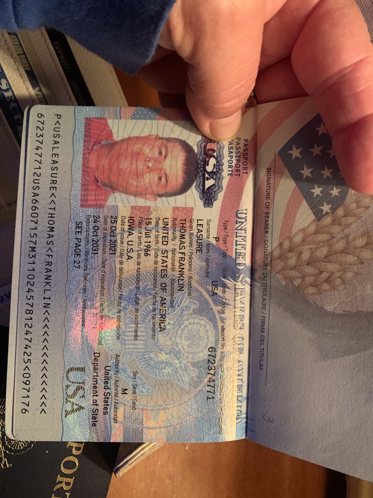 a person holding up a passport with an american flag design on it's front