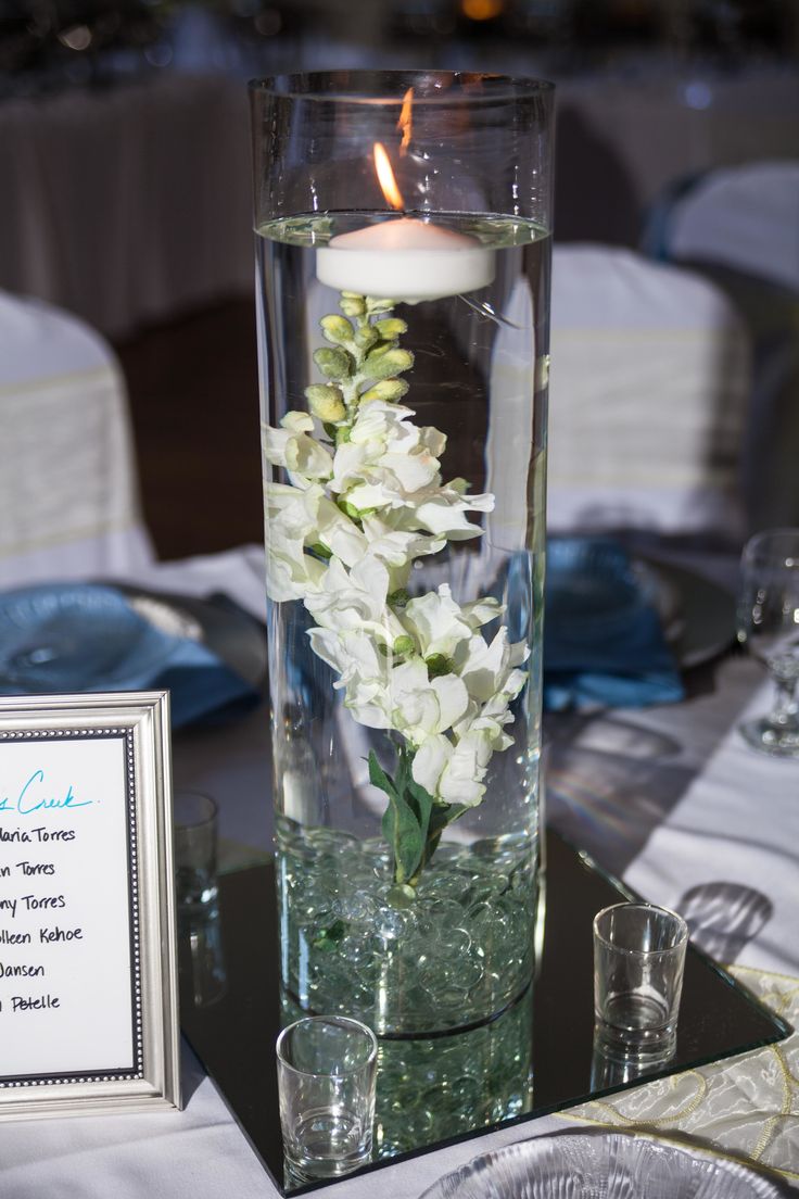 a vase filled with water and flowers on top of a table next to a framed sign