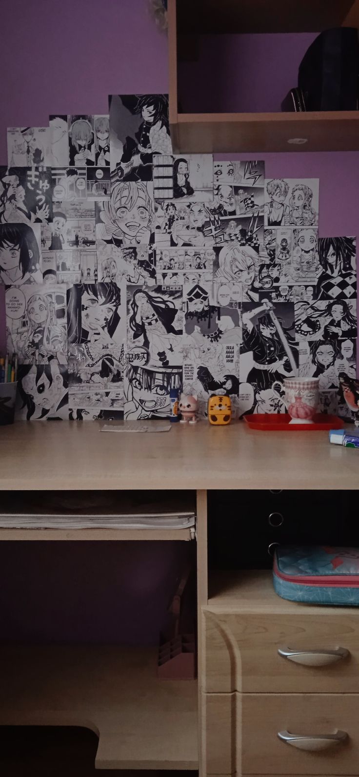 a wooden desk topped with lots of comics on top of purple walls and drawers next to it