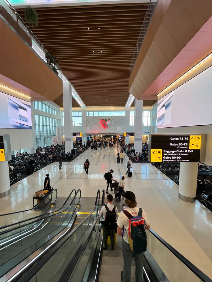 people are riding down an escalator at the airport