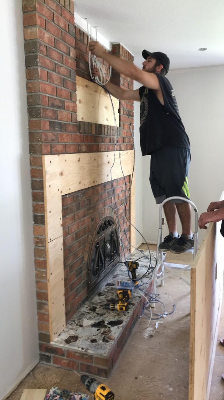 a man standing on top of a chair next to a fire place