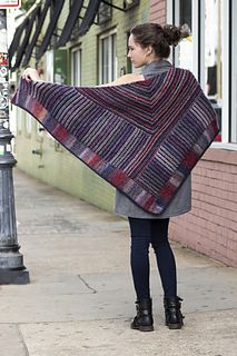 a woman is standing on the sidewalk holding a shawl