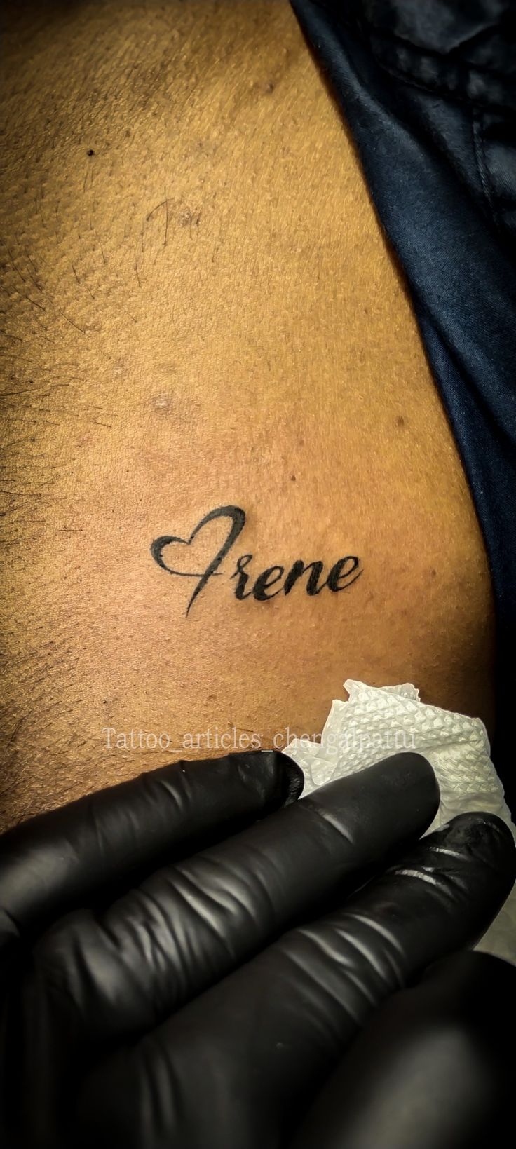 a person with black gloves on their arm and the word frene written in cursive ink