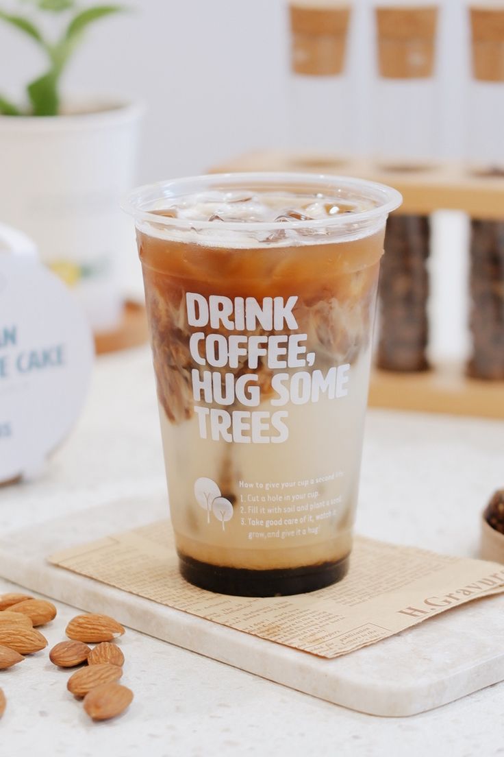 a cup of coffee sitting on top of a table next to almonds and other items