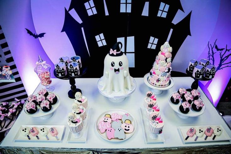 a table topped with lots of cupcakes and halloween themed desserts on top of it