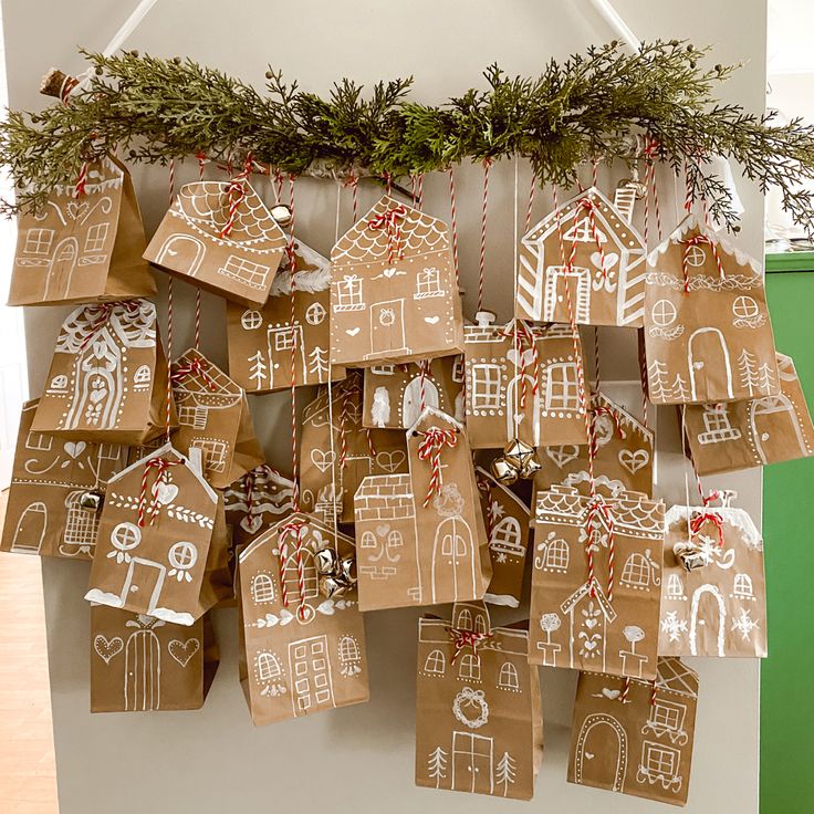 gingerbread houses are hung on the wall with twine ribbons and decorated christmas tree branches