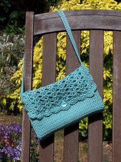 a crocheted purse sitting on top of a wooden bench