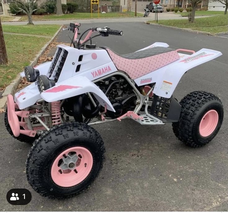 a pink and white atv is parked on the street