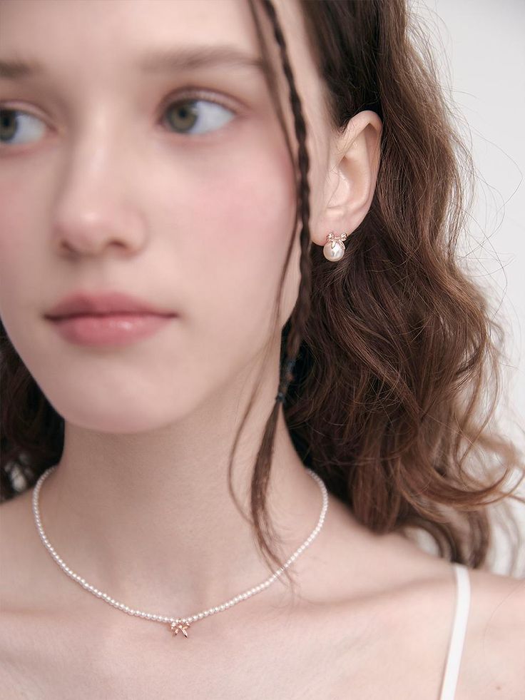 a young woman wearing a necklace and earrings