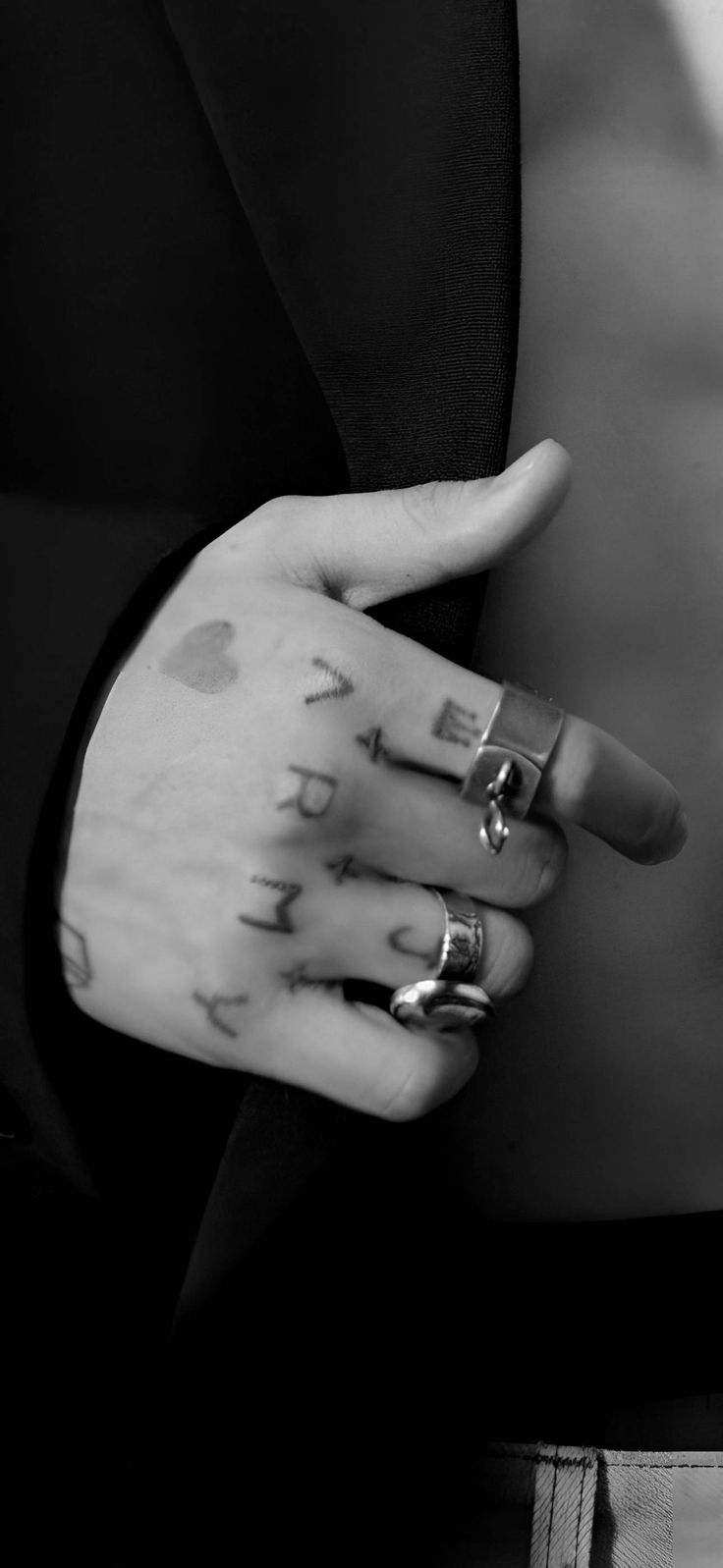 black and white photograph of a woman's hand with rings on her fingers holding an apple