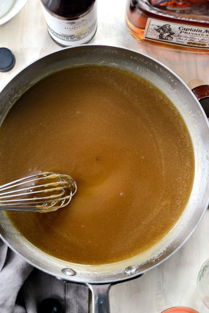 a pot filled with liquid and whisk on top of a table next to bottles