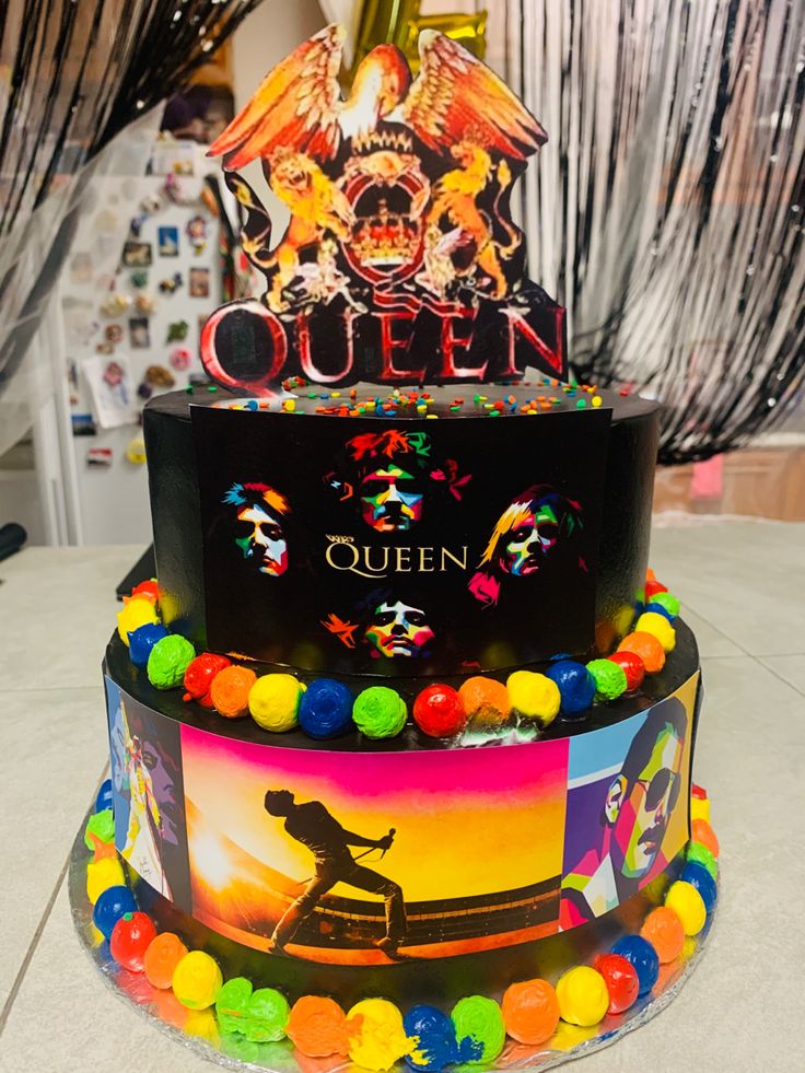 a three tiered cake decorated with colorful candies and an image of queen on top