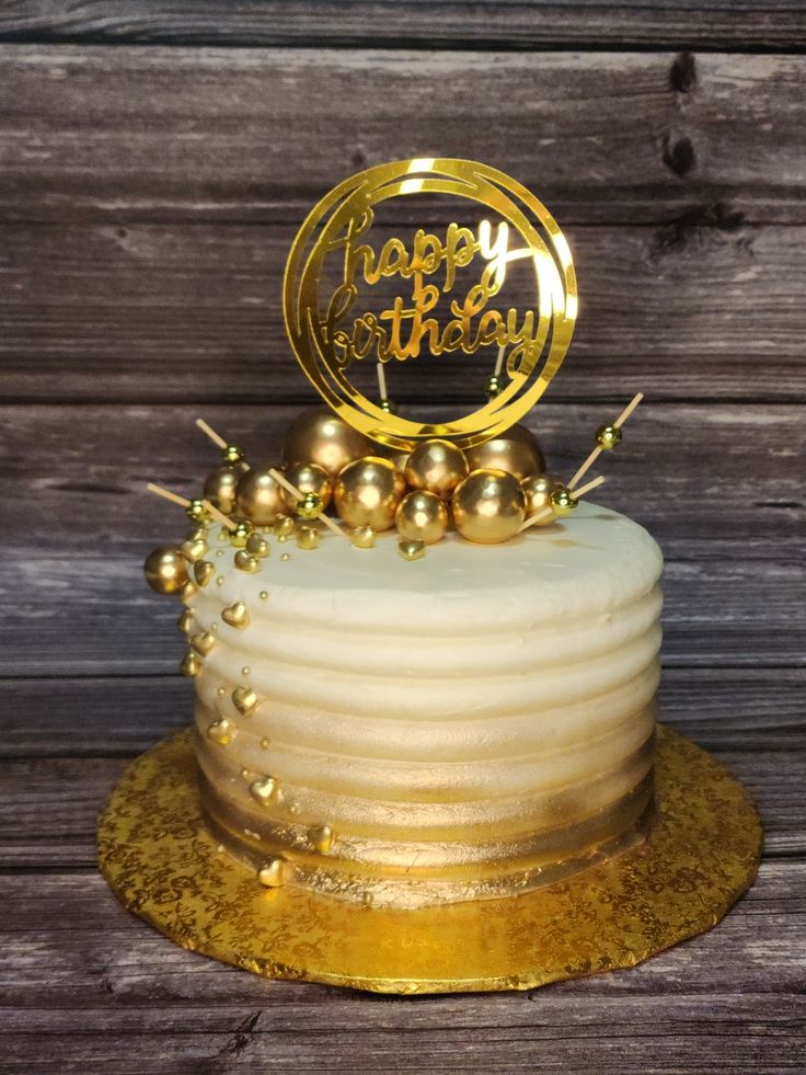 a white cake with gold decorations and a happy birthday sign on top