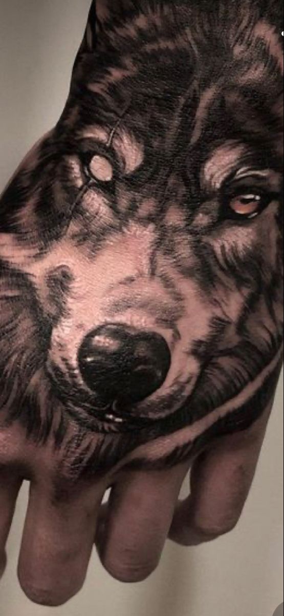 a man's hand with a wolf tattoo on it