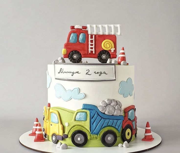 a birthday cake with a truck on top and traffic cones around the edges, is decorated in white frosting