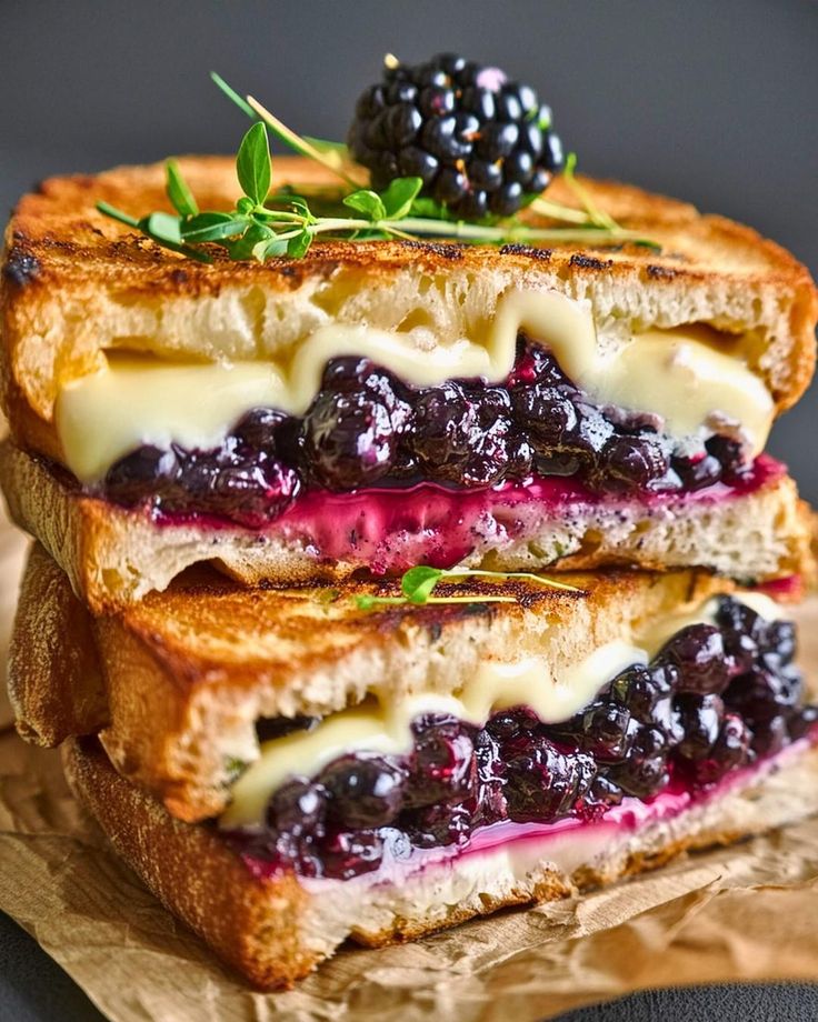 two grilled sandwiches with blueberries and cream cheese on them are stacked on top of each other