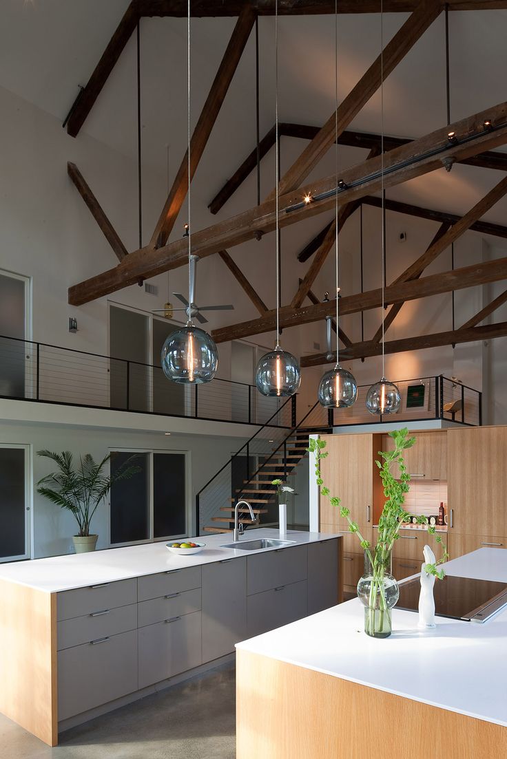 a kitchen with wooden beams and hanging lights above the countertop, along with a plant in a glass vase