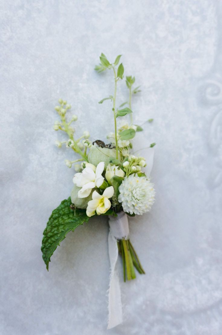 a bridal bouquet with white flowers and green leaves on a snow - covered surface