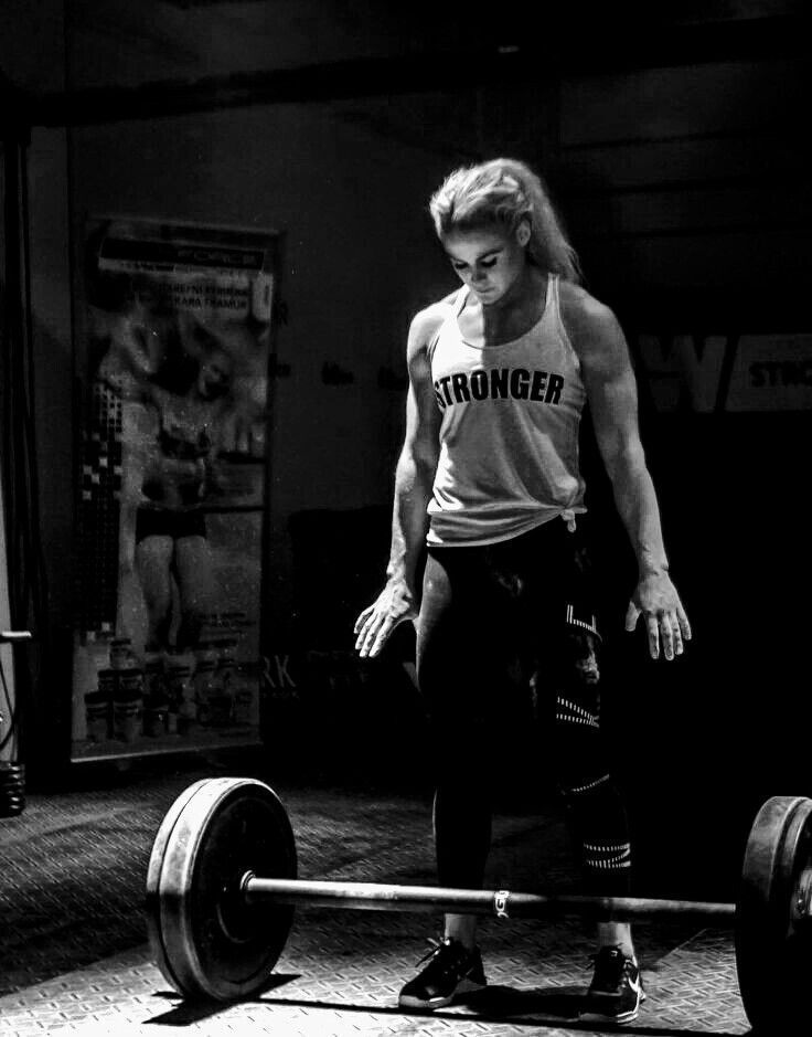 a man standing next to a barbell in a gym