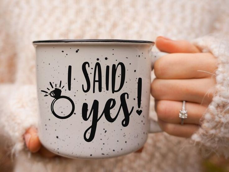 a woman holding a coffee mug with the words i said yes on it in black ink