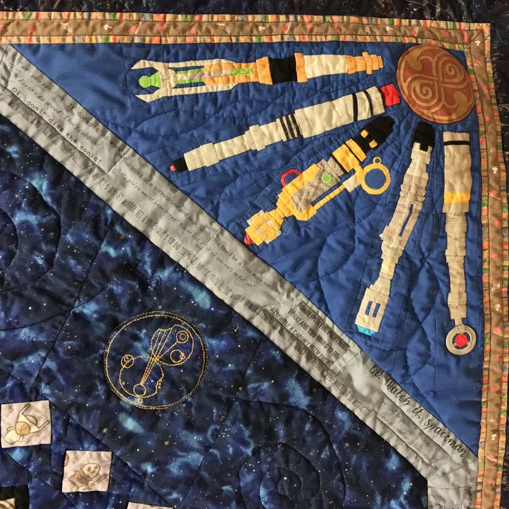 a quilted wall hanging with space themed items on it