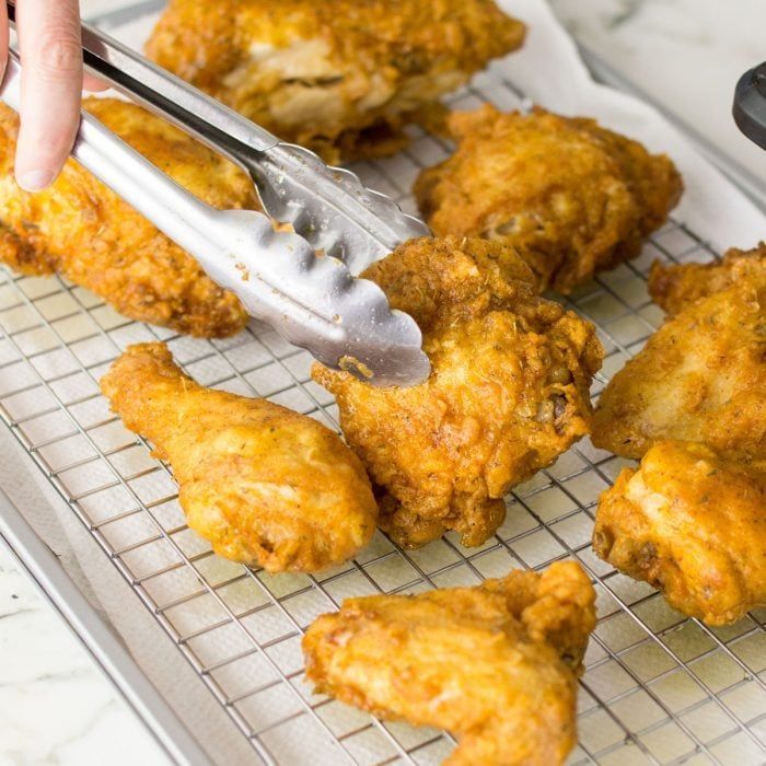 someone is cutting chicken wings on a wire rack