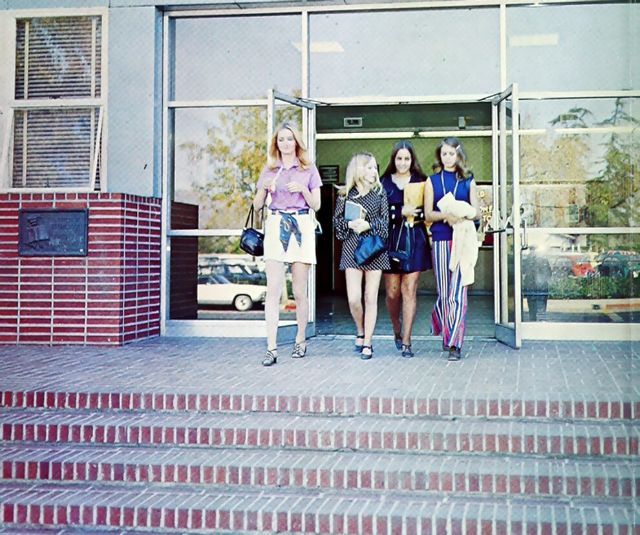 three young women are standing in front of a building